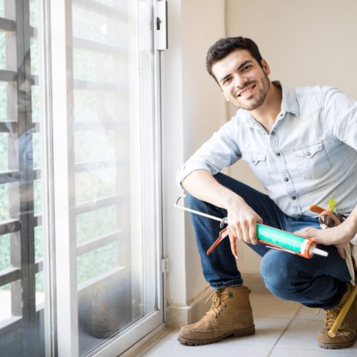 good-looking-young-handyman-just-finished-sealing-door-frame-looking-satisfied-with-his-work (1)